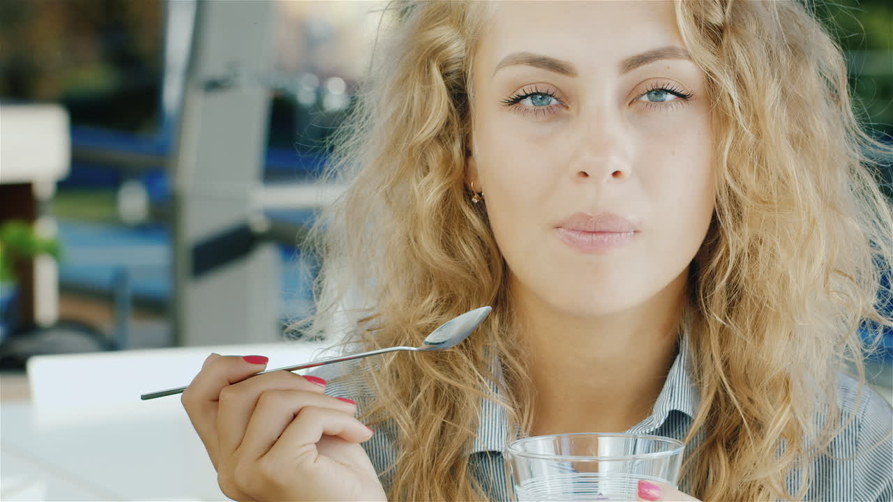 카메라에 미소 카페에서 아이스크림을 먹고 매력적인 젊은 여자