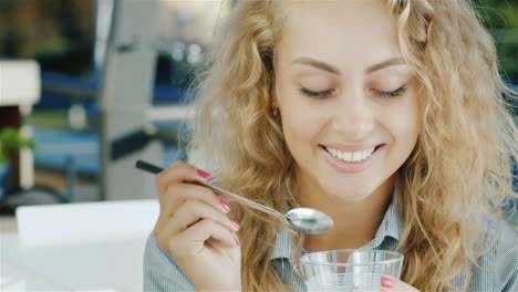 attractive young woman eating ice cream in cafe smiling at the camera