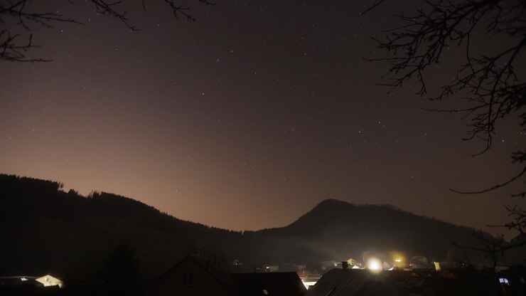 Timelapse notturno di case che inquinano l'ambiente con combustibile solido in una notte stellata in un villaggio, Slovacchia