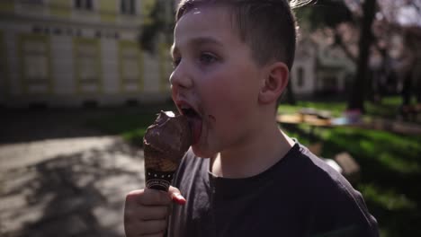 close-up of a boy savoring a chocolate ice cream cone, with chocolate smears on his face