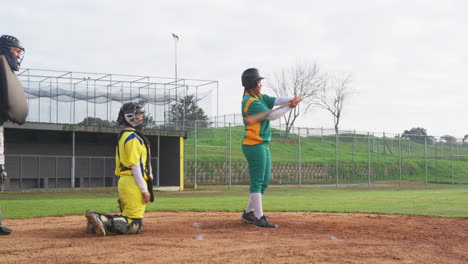 multiracial female baseball players and male umpire, hitting and throwing the ball on a pitch