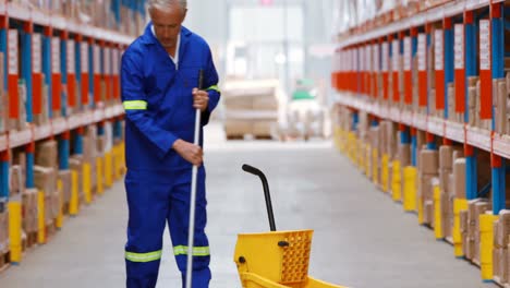 male warehouse worker moping floor