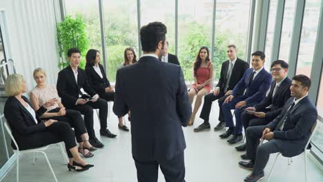vista trasera de un hombre de negocios de pie en el podio dando un discurso dirigiéndose a una conferencia en un seminario. presentación del hombre ejecutivo en una reunión en la oficina en la ventana con colegas