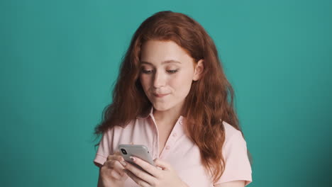 redheaded girl in front of camera on turquoise background.