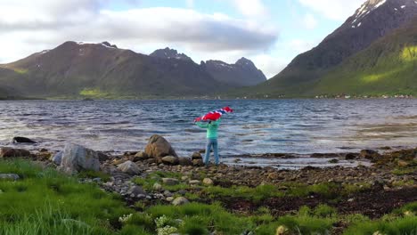 mujer con una bandera de noruega ondeando en el fondo de la naturaleza