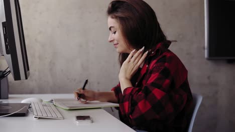 Young-attarctive-girl-is-writing-something-down-with-one-hand-while-holding-her-hair-with-another.