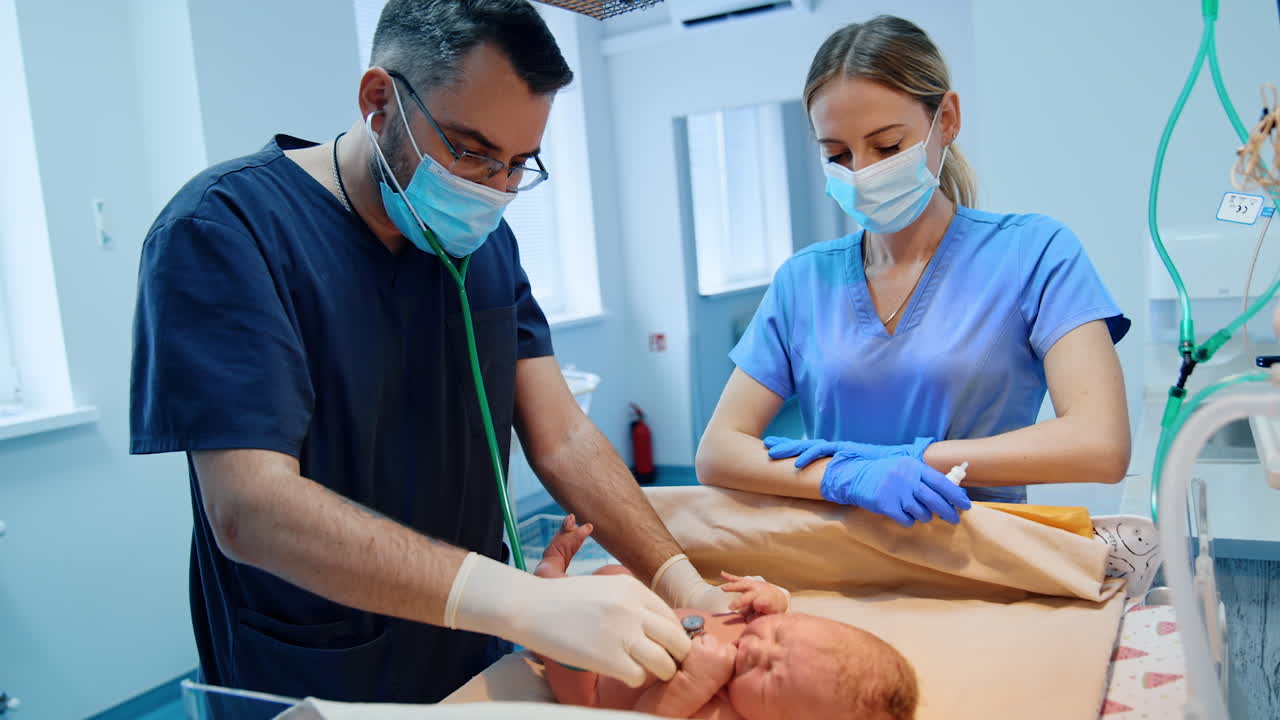 Pediatrician uses stethoscope to listen to baby's heart and breathing. Newborn is examined after birth. Nurse is standing beside.