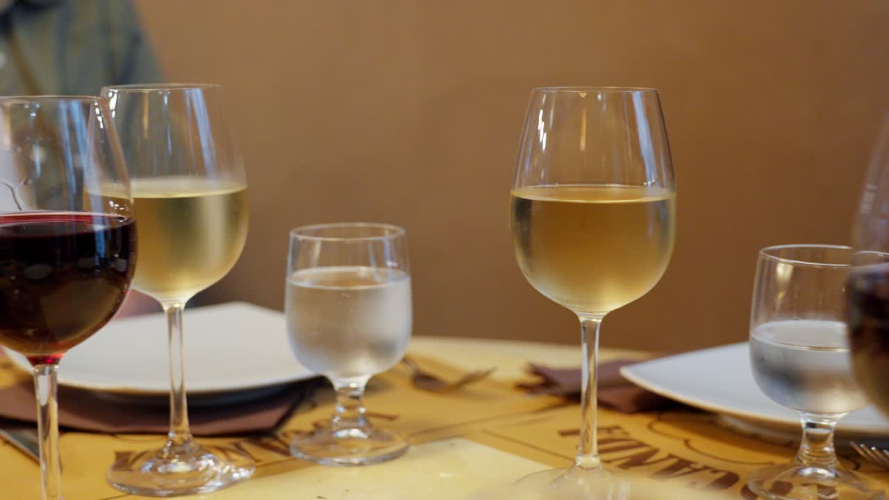 Primer plano de copas de vino, vaso de agua y platos vacíos en una mesa de comedor en un restaurante