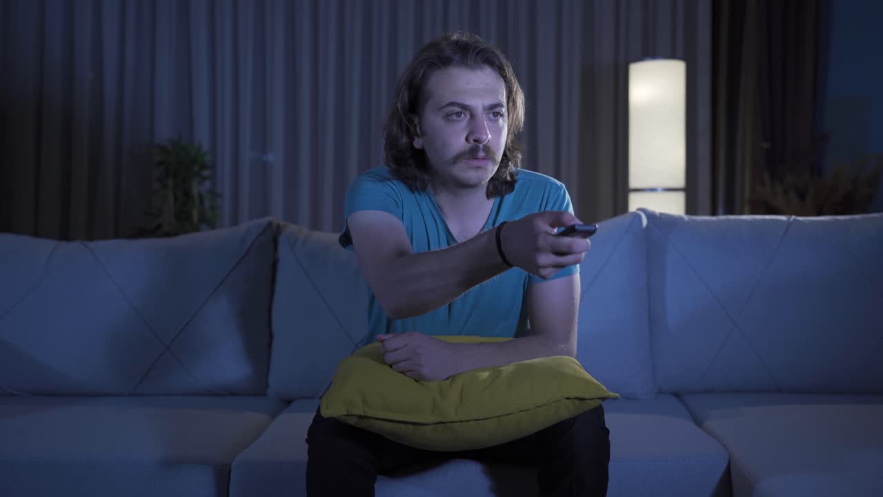 el hombre que mira la televisión por la noche mira con asombro y asombro.