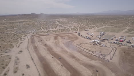 Panorámica-Aérea-De-Carreras-De-Autos-En-Una-Pista-De-Carreras-De-Tierra-En-El-Desierto-De-Mojave,-California