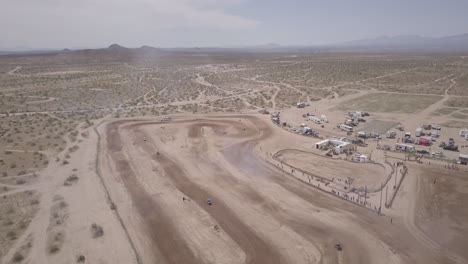 panorámica aérea de carreras de autos en una pista de carreras de tierra en el desierto de mojave, california