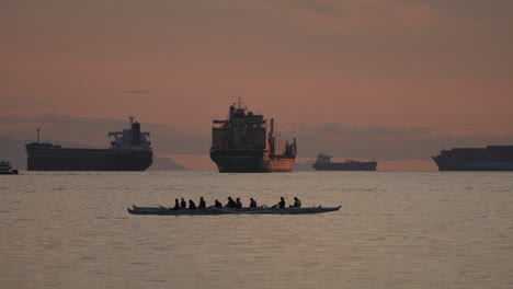 silhouetted group of people riding on a paddle boat on water surface in vancouver, canada at sunset