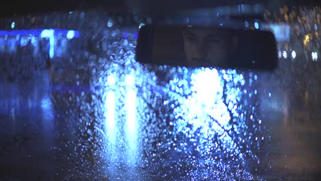 the young man sits in the car on the rainy evening