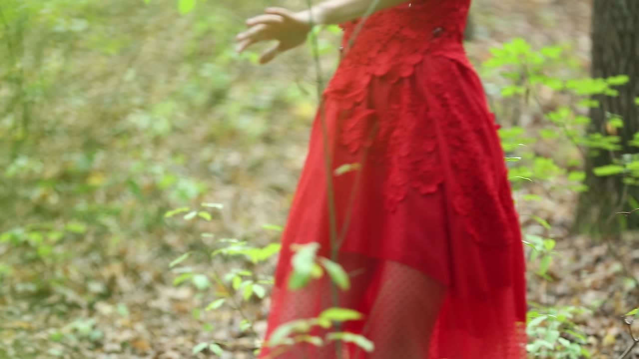Beautiful Woman Walking Through Green Forest. Beautiful woman in red long dress walking through green forest