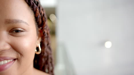 smiling woman with braided hair wearing hoop earrings, close-up portrait, copy space