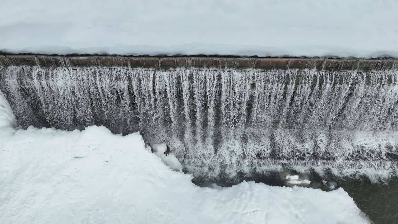 Frozen waterfall cascading over a dam in winter, creating a serene and icy landscape