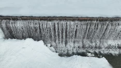 frozen waterfall cascading over a dam in winter, creating a serene and icy landscape