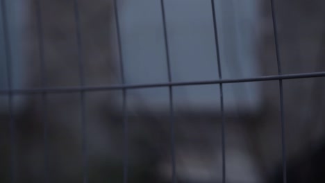 View-of-building-background-through-metal-fence-railings