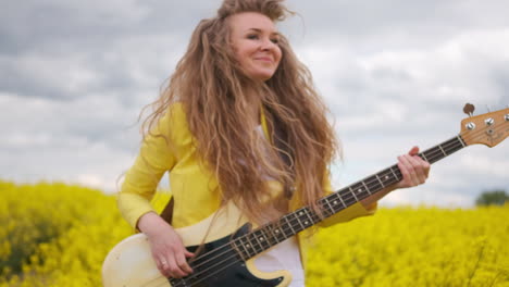 a woman plays a rock or metal guitar jumps and dances shaking her head and hair. the live camera moves along with the guitarist in a yellow suit.