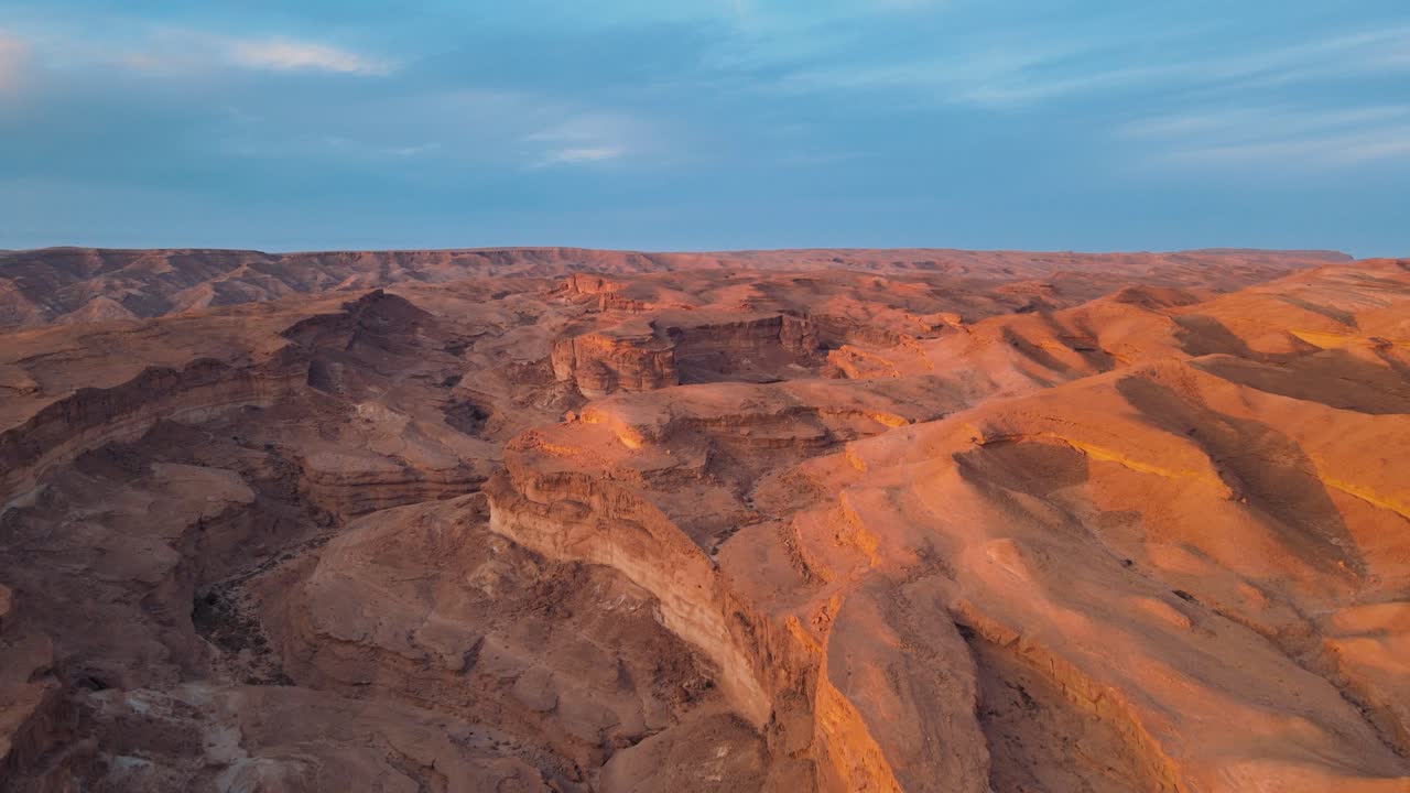 A stunning sunset casts a warm glow over the mountains in Africa, creating beautiful orange hues on the sand dunes of the desert.