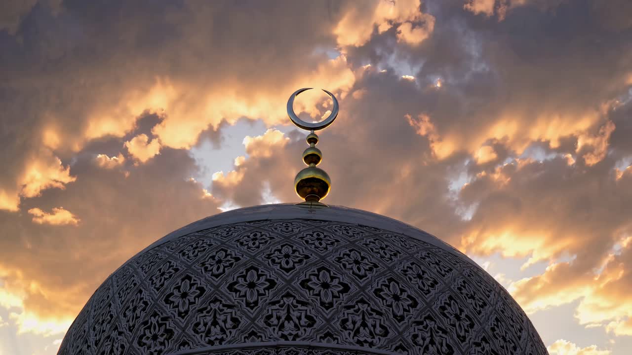 Low-angle shot of a mosque dome with intricate patterns, set against a dramatic sunset sky