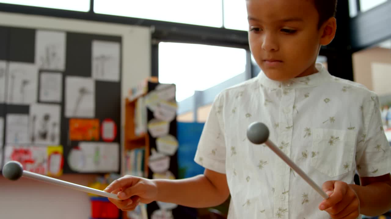 vista frontal de un escolar asiático tocando el xilófono en un aula de la escuela 4k