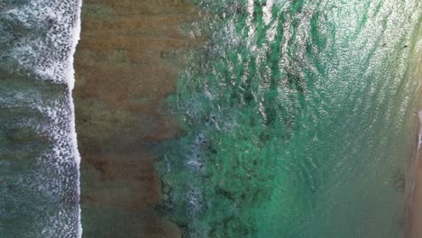 Aerial-Top-Down-View-of-Foamy-Wave-Rolling-Breaking-Over-Melasti-Sandy-Beach-in-Uluwatu-Bali-Indonesia