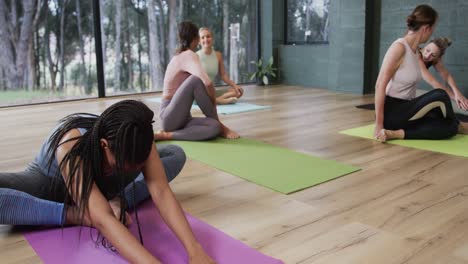 Fokussierte,-Vielfältige-Frauen,-Die-Sich-Gemeinsam-Auf-Matten-Im-Yoga-Kurs-Mit-Einer-Trainerin-Dehnen,-Zeitlupe
