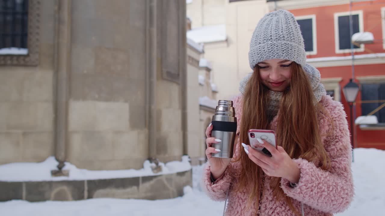 joven viajera caminando por la ciudad vieja sosteniendo un teléfono móvil, charlando con amigos y familiares