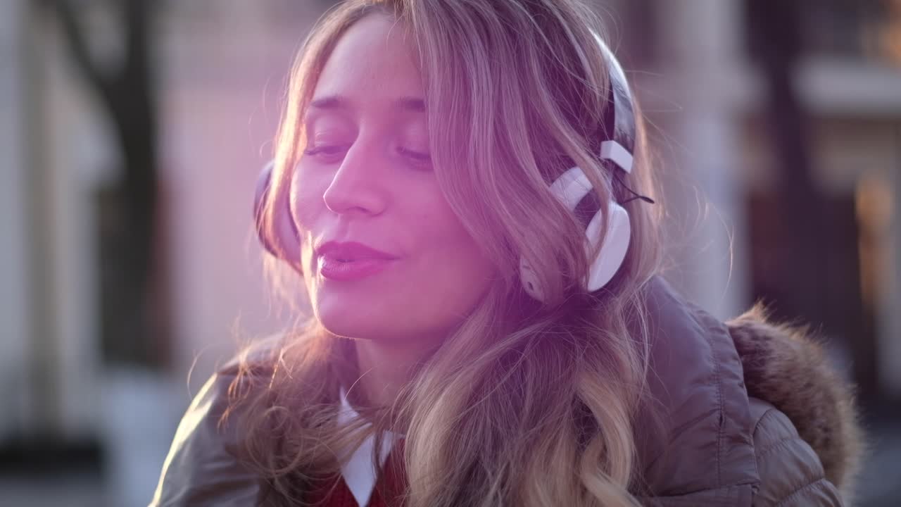 Woman listening to music in her headphones while singing along and dancing in the street
