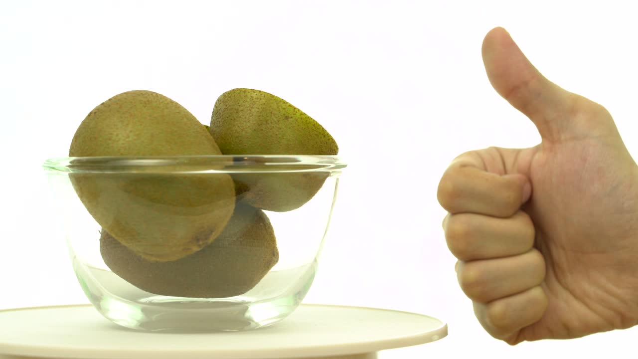 kiwis frescos, maduros y verdes en un cuenco giratorio con la mano