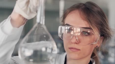 closeup portrait of female scientist examining liquid in test tube with magnifier