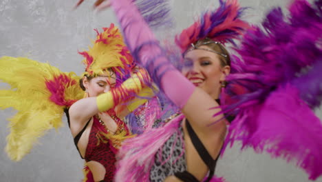 three cabaret girls in colorful gowns dancing while the camera is approaching them