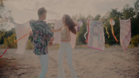 Young-couple-dancing-bachata-against-sarongs-at-beach