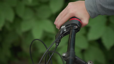 close-up of someone in hash cloth, gripping the handlebar of a bicycle while riding along a scenic path surrounded by lush greenery with background slightly blur