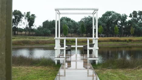paisaje tranquilo en un pequeño lago con sillas vacías en un muelle privado - plano general