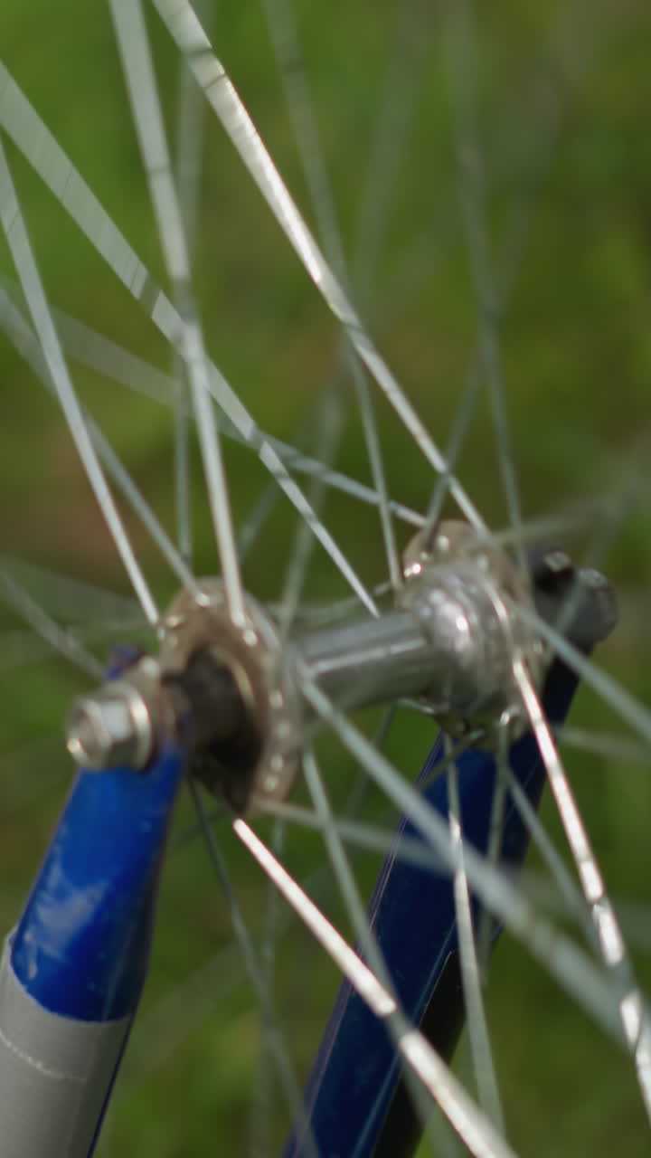 primer plano de una bicicleta colocada al revés con su neumático trasero girando lentamente, el enfoque está en la rueda y los radios, mientras que el fondo de la vegetación permanece suavemente borroso