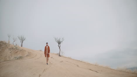 man in a brown suit walking on a hilltop