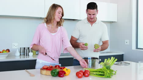 una pareja sonriente preparando una cena saludable juntos