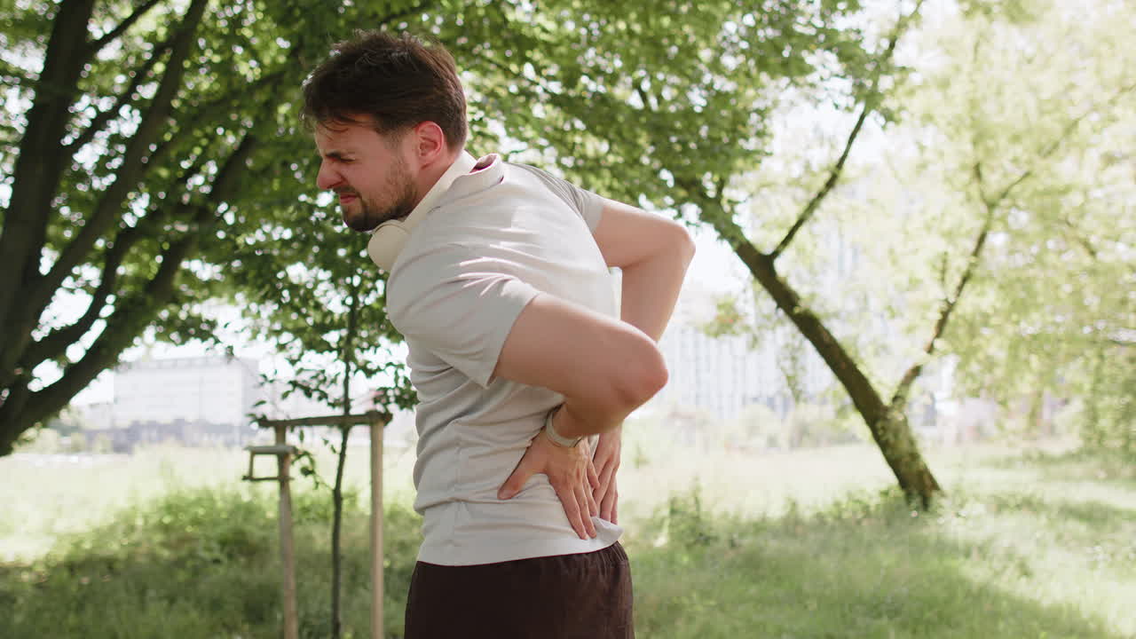 Young runner man suffering from back pain sports injury muscle spasm flank ache in city park