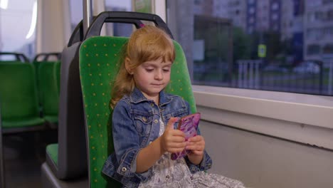 Young-little-child-girl-kid-in-city-train,-tram-or-bus-using-smartphone-chatting-with-friends