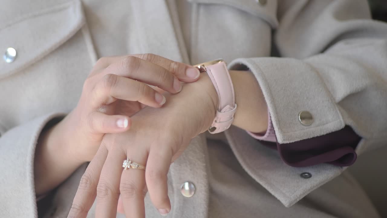 Primo piano di una mano che regola uno smartwatch rosa