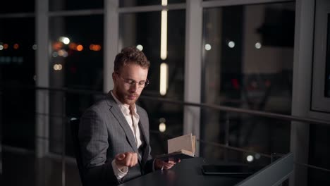 handsome young man in a business suit writes notes in a diary