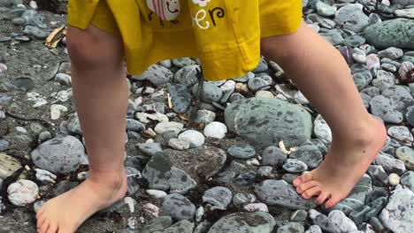 girl walking barefoot across stones on beach