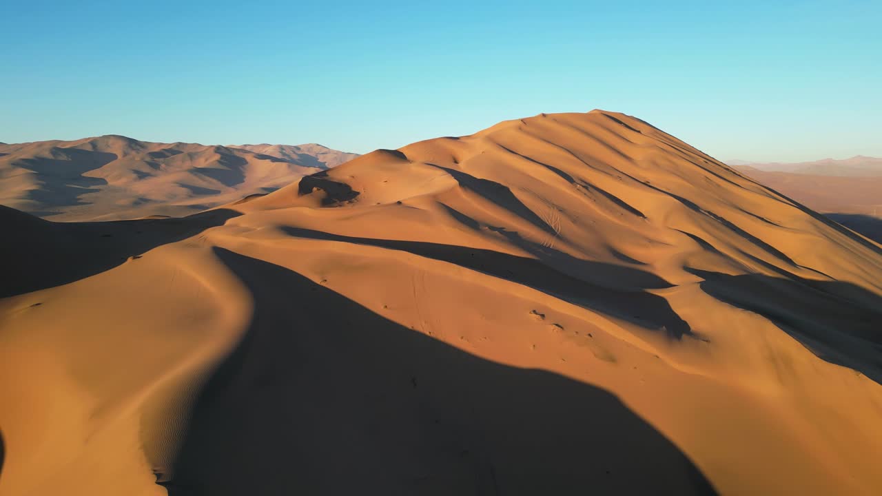 Drone shot of the Whale Dune in the Atacama, showing vast desert curves painted with shimmering light and shadow