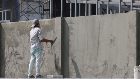 a construction worker applies plaster to a wall.