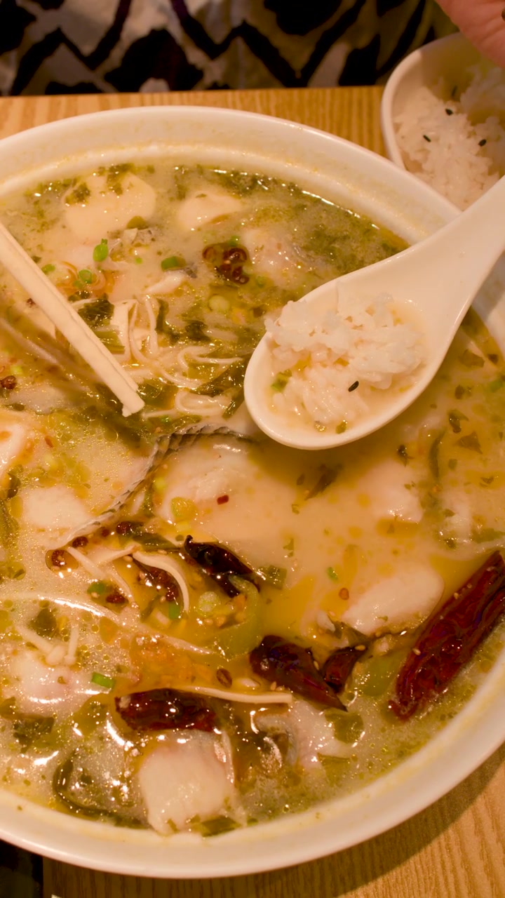 Fugleperspektiv af krydret fiskesuppe serveret med hvide ris og spisepinde på restaurant