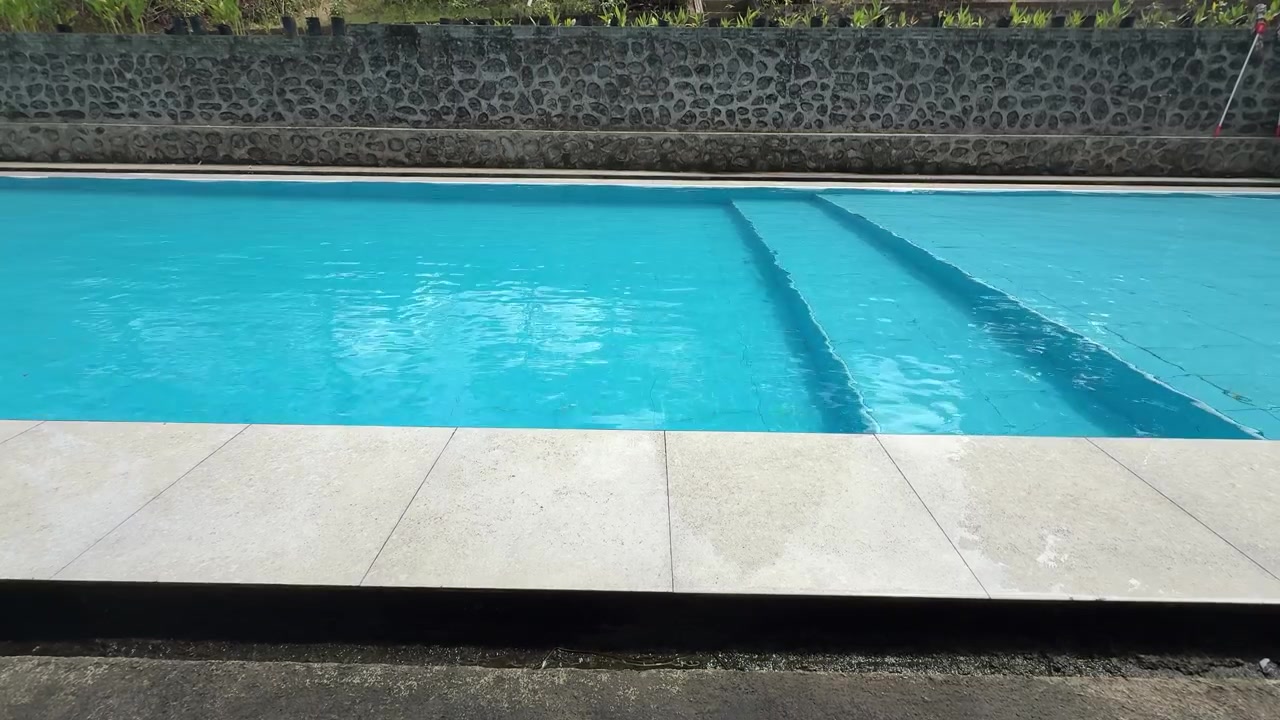 Piscina blu limpida con sfondo di muro in pietra