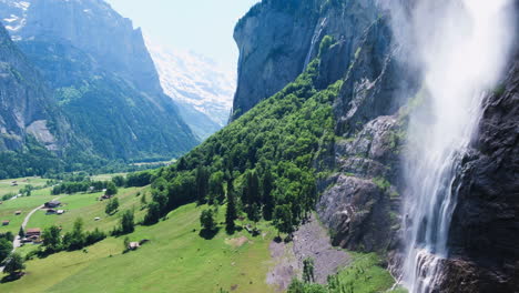 Disparo-De-Dron-Calmante-Flotando-Cerca-De-Una-Gran-Cascada-Icónica-Que-Fluye-Hacia-El-Valle-Al-Mediodía-En-Lauterbrunnen,-Suiza,-Europa,-Vista-Amplia