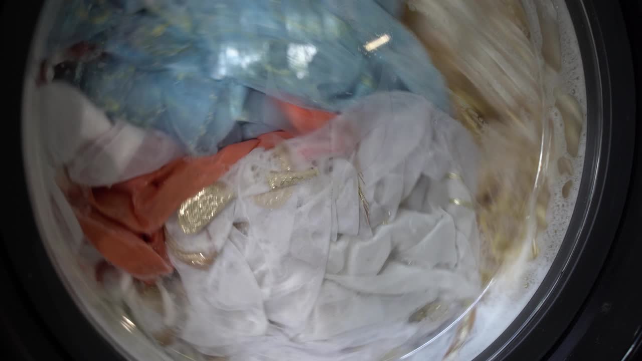 클로즈업 산업용 세탁기는 다채로운 옷과 색 린, 색 줄무 옷을 세탁합니다. 실린더 스피닝 머신. 개념 세탁기 세탁기, 산업 세탁 서비스